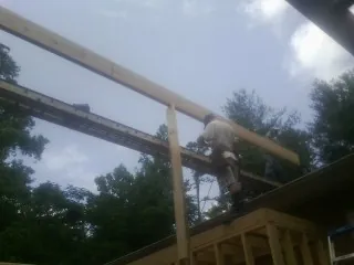 Carpenter setting a ridge beam over a new addition frame — Ice Dam Removal by Roofing Brothers in Hanceville