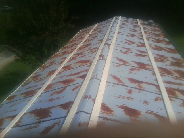 Rusted metal roof panels with new wood purlins before replacement — Storm Damage Roof Repair in Hanceville by Roofing Brothers