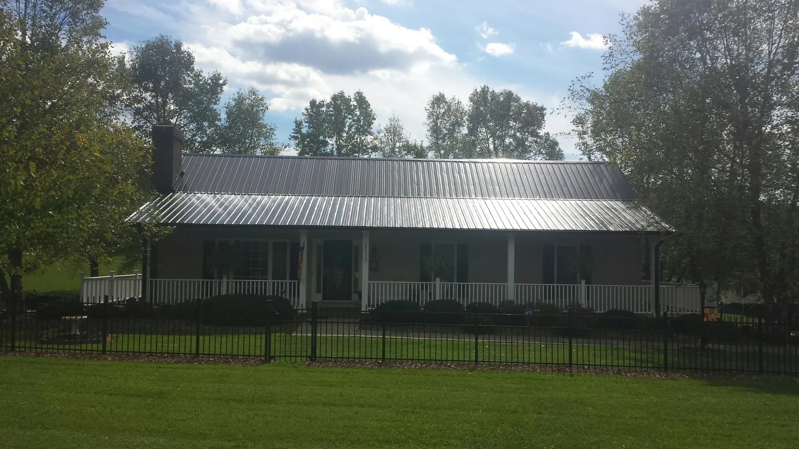 Gray metal roof on a brick ranch with a full width front porch — Gutter Guard Installation work by our crew in Hanceville