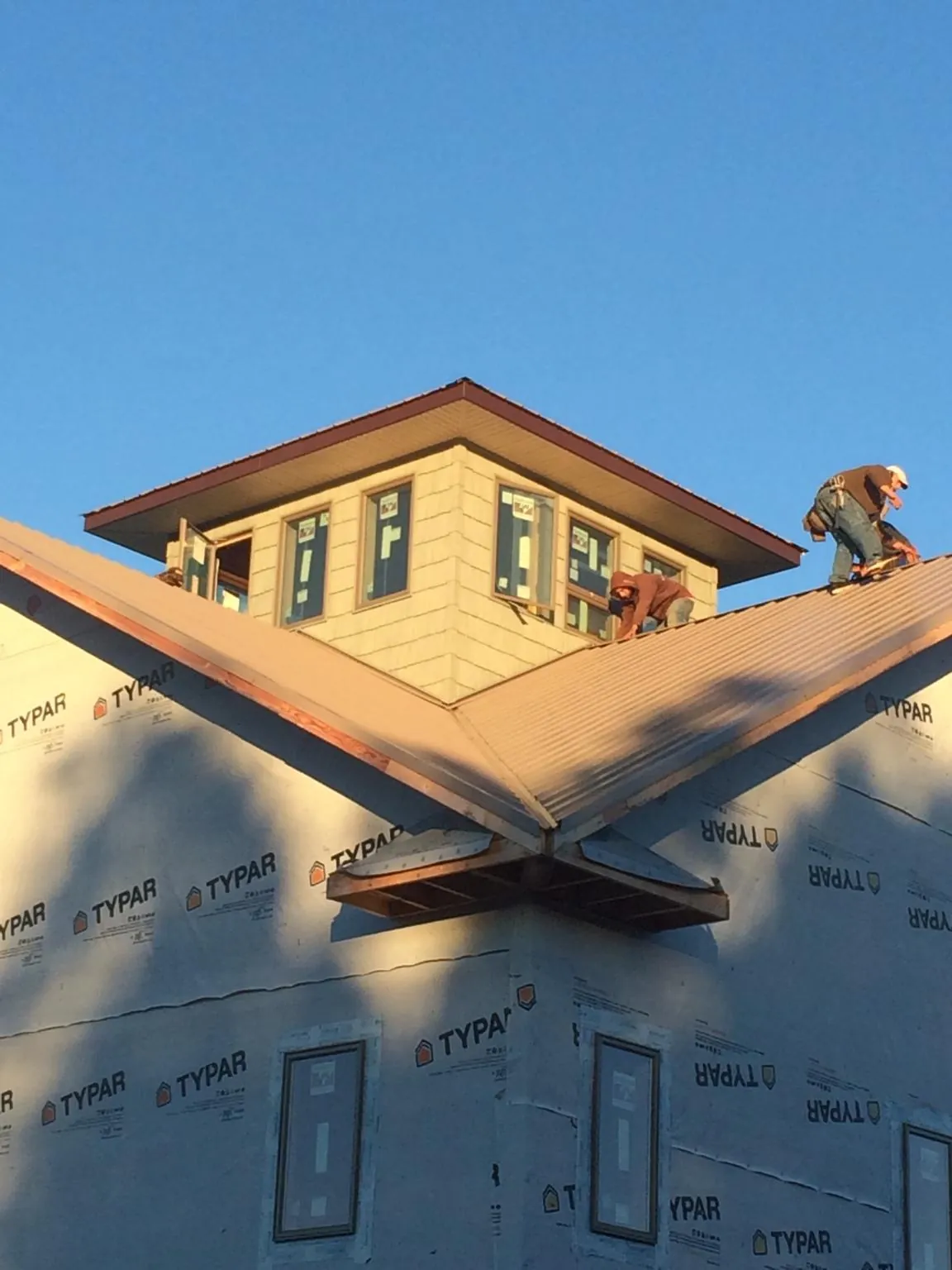 Roofers working around a rooftop cupola on a new metal roof at sunset — Roof Waterproofing in Hanceville by Roofing Brothers